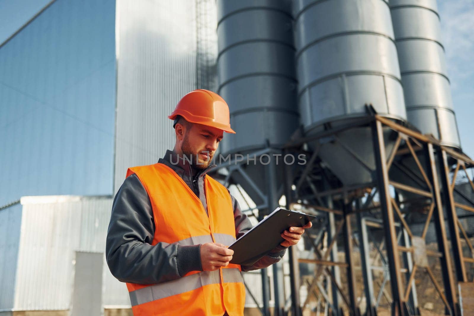 Building exterior. Construction worker in uniform is outdoors near the factory.