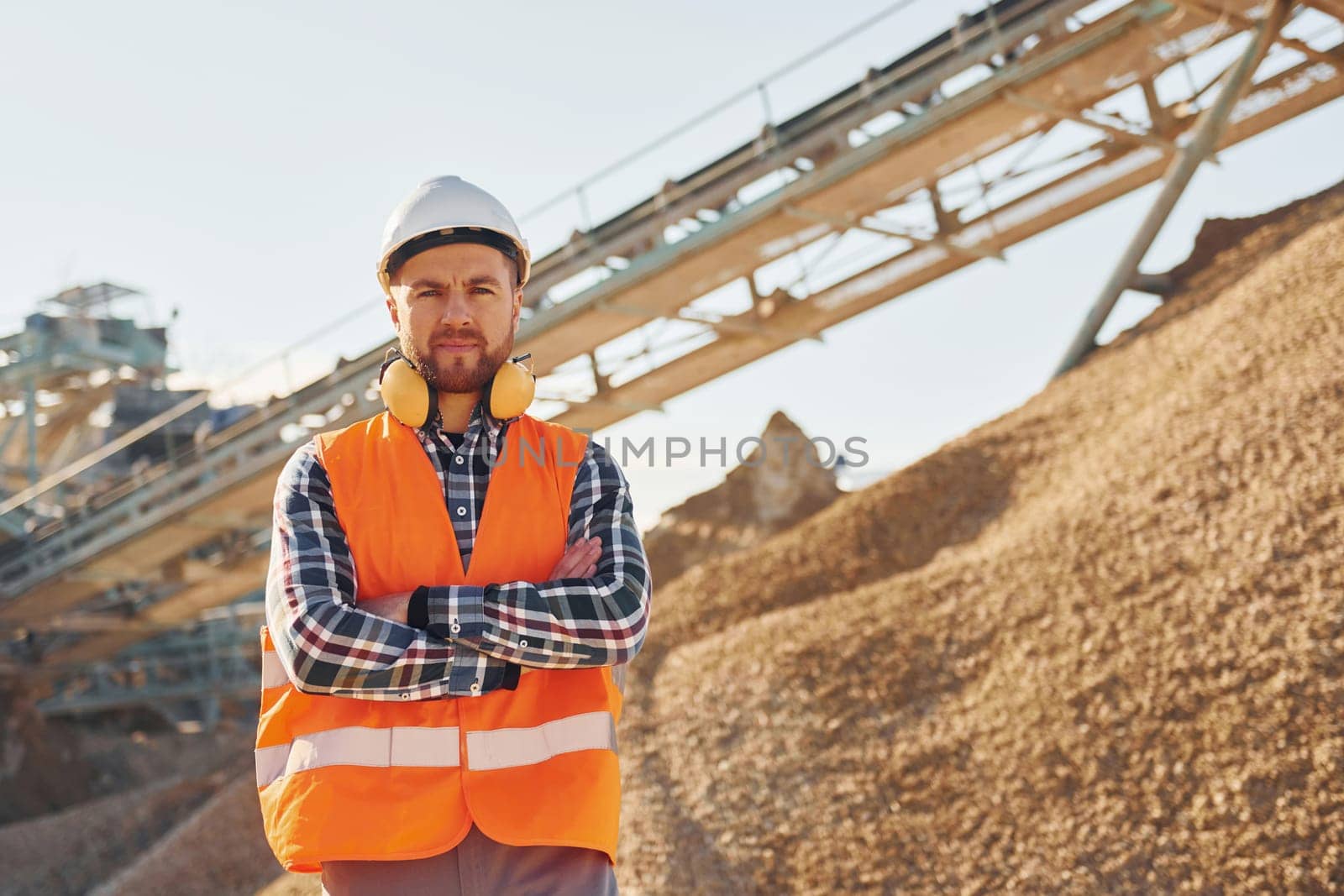 Heavy transport behind. Construction worker in uniform is on the quarry.