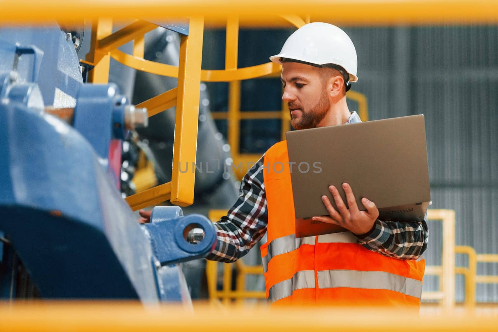 Close up view. Construction worker in uniform is in the factory.