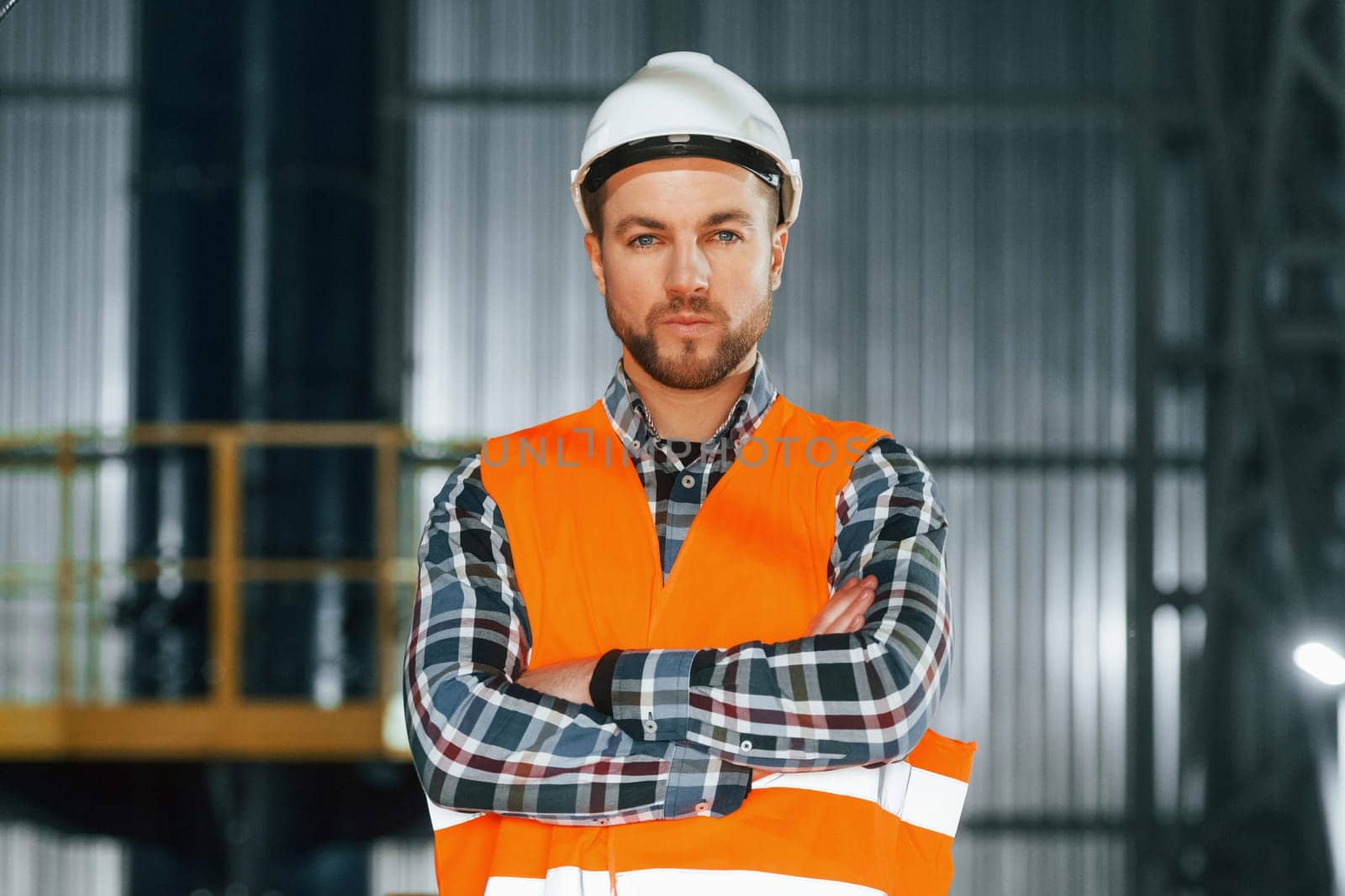 Close up view. Construction worker in uniform is in the factory.