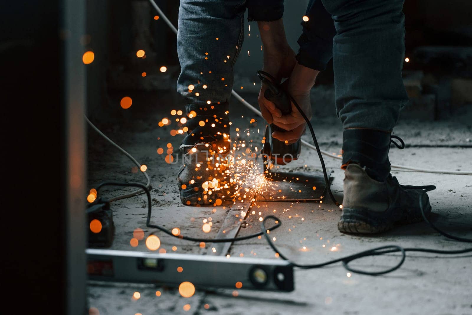 Sparks flying. Close up view of man's legs and hands with slicing tool. Working with metal.