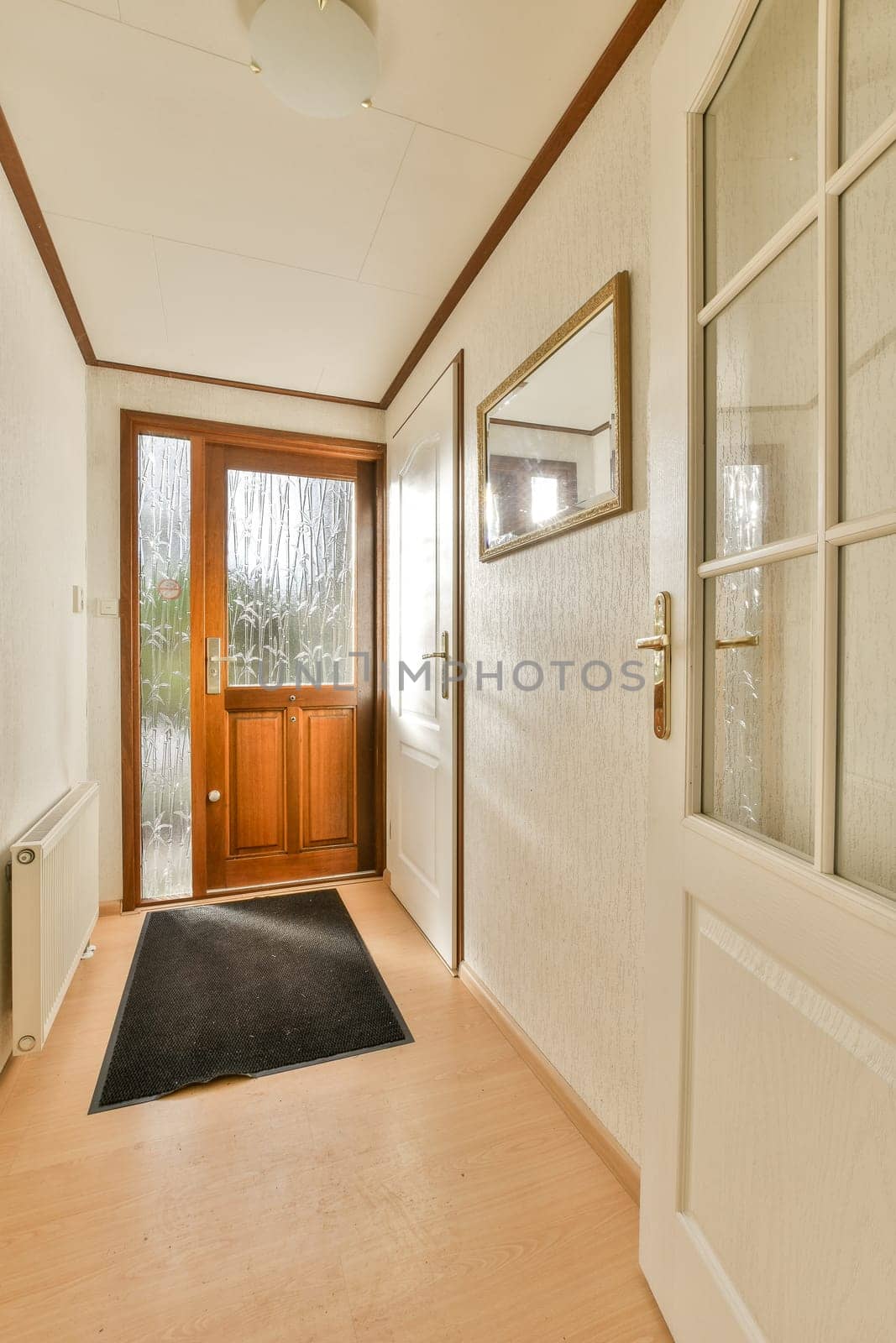 a long hallway with wood flooring and white wallpaper on the walls there is a black rug in front of the door