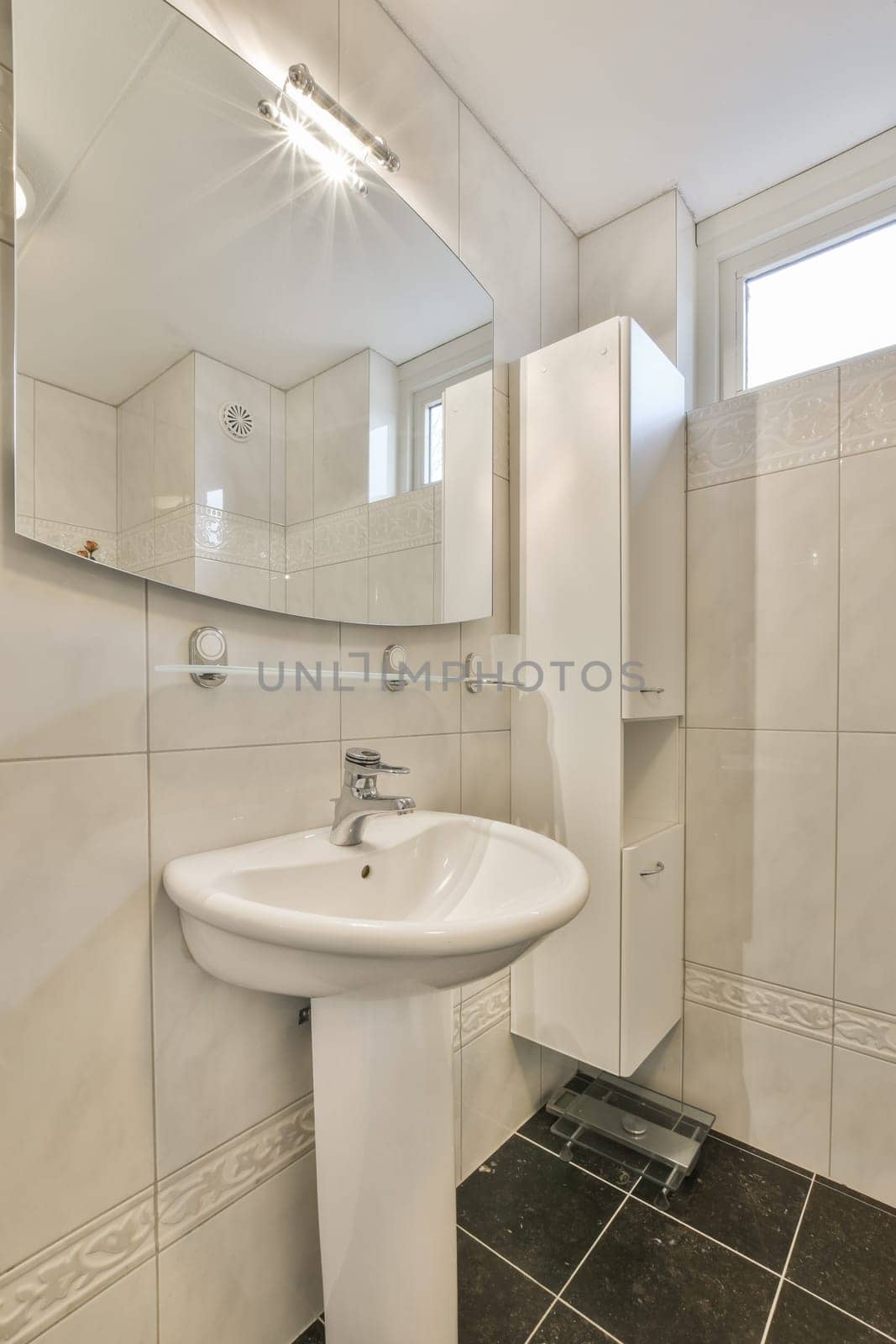 a bathroom with a sink, mirror and toilet paper on the wall next to it is a black tile floor