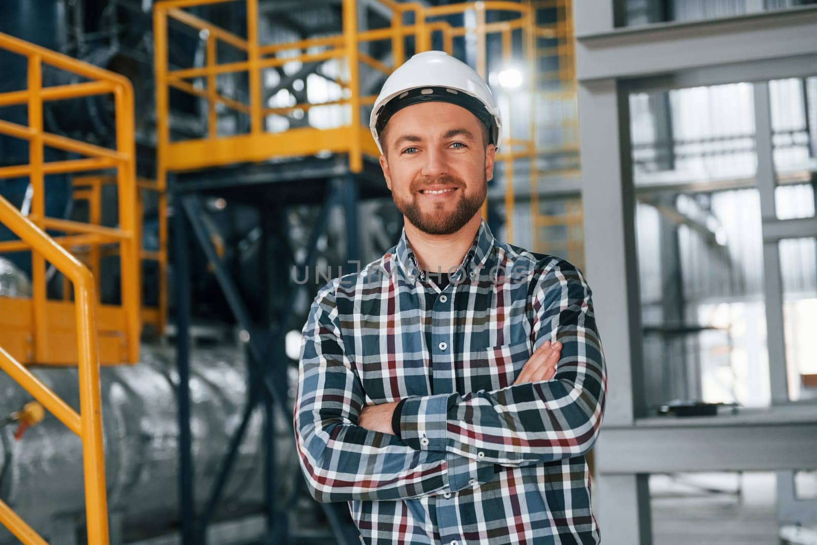 Posing for camera. Construction worker in uniform is in the factory.