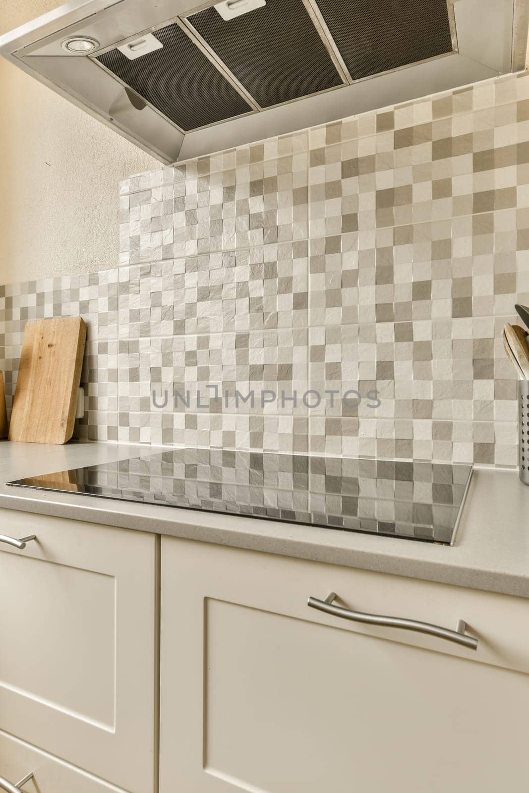 a kitchen with white cabinets and gray tiles on the backs of the range hood over the sink is in front of the stove