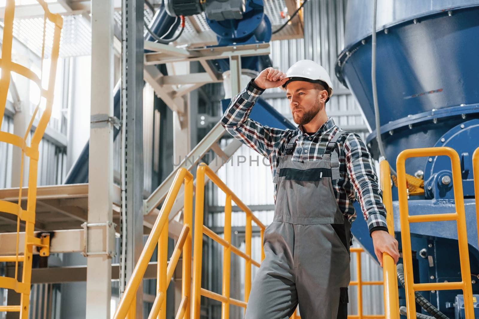 Engineer is indoors. Construction worker in uniform is in the factory.