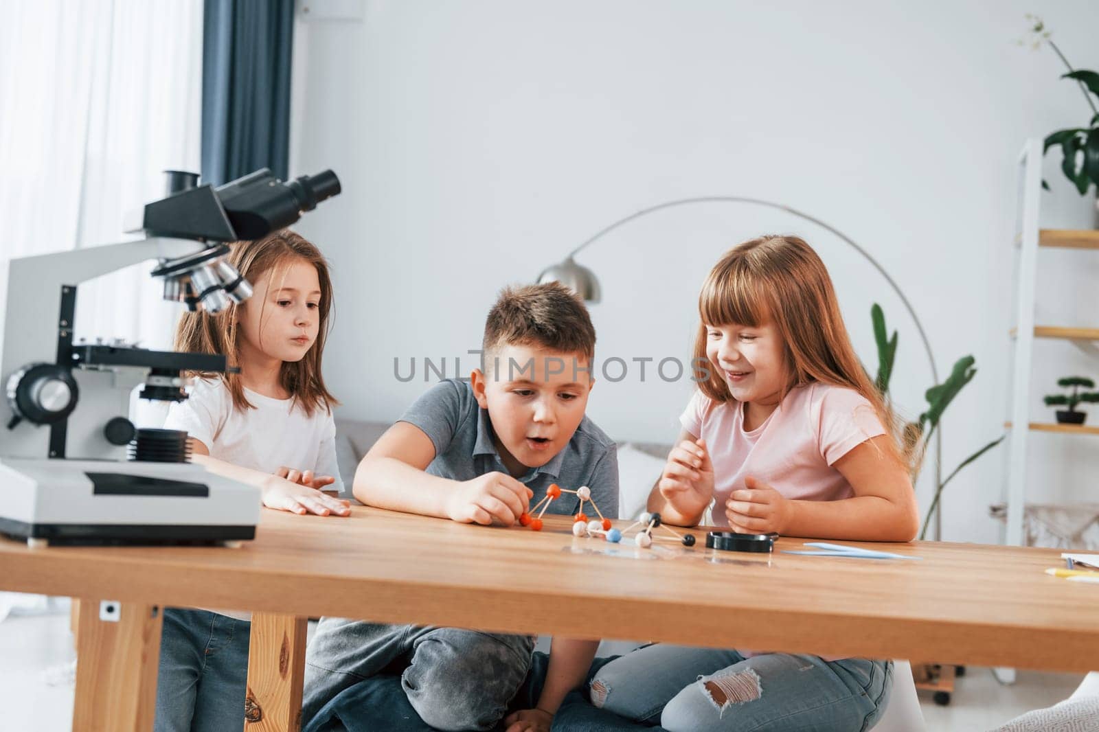 Using microscope. Kids having fun in the domestic room at daytime together.