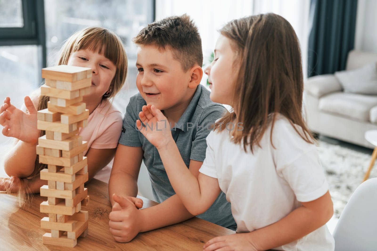 Building a tower. Playing game. Kids having fun in the domestic room at daytime together.