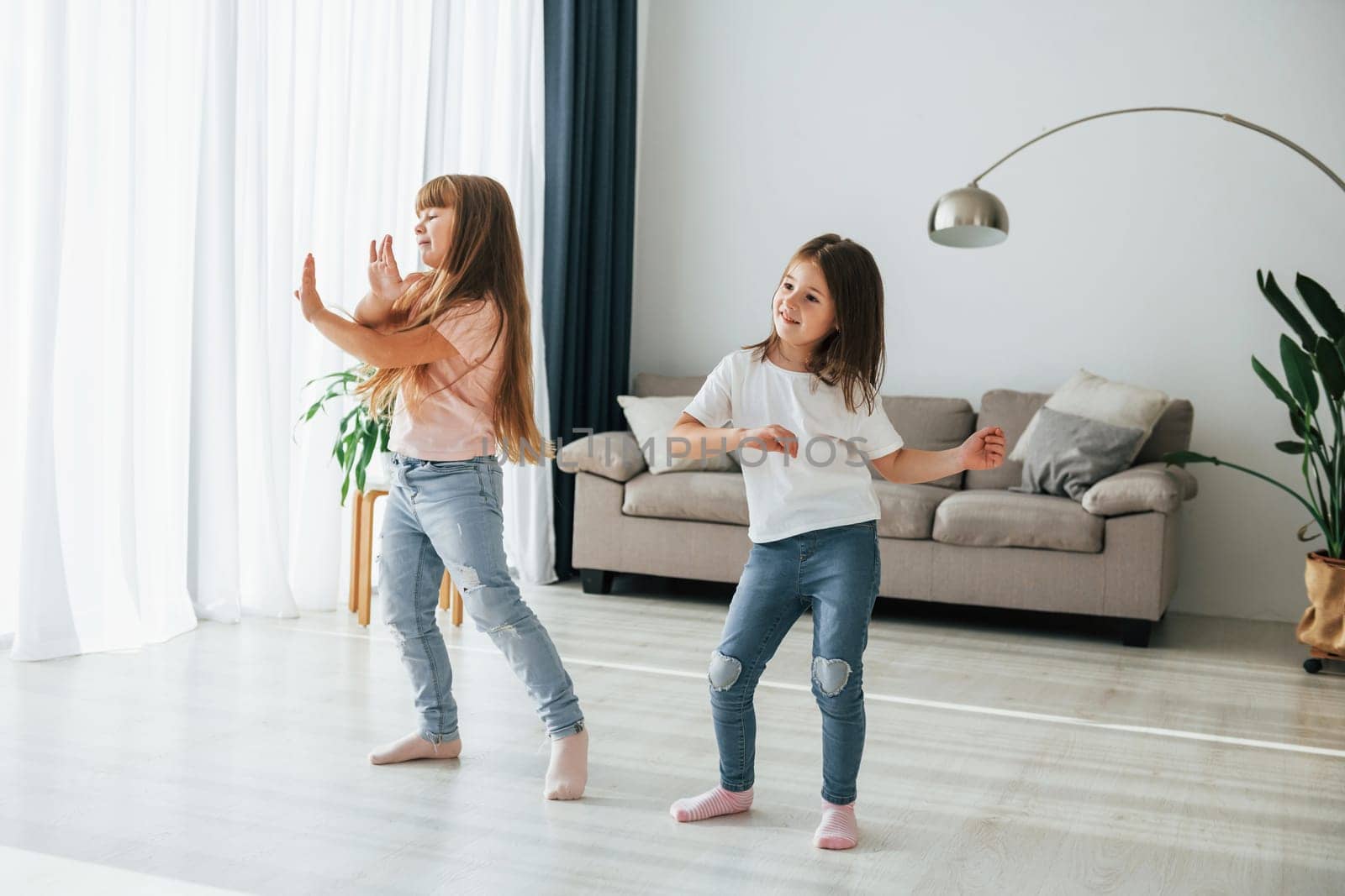 Dancing together. Kids having fun in the domestic room at daytime by Standret