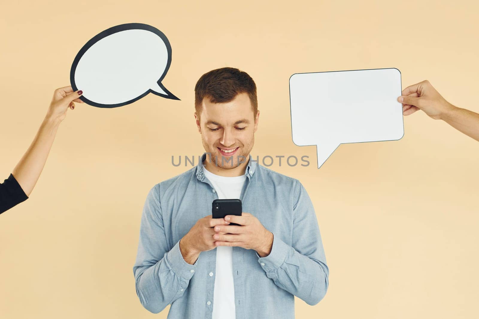 Holding smartphone. Many ideas. Man standing in the studio with empty signs for the text.