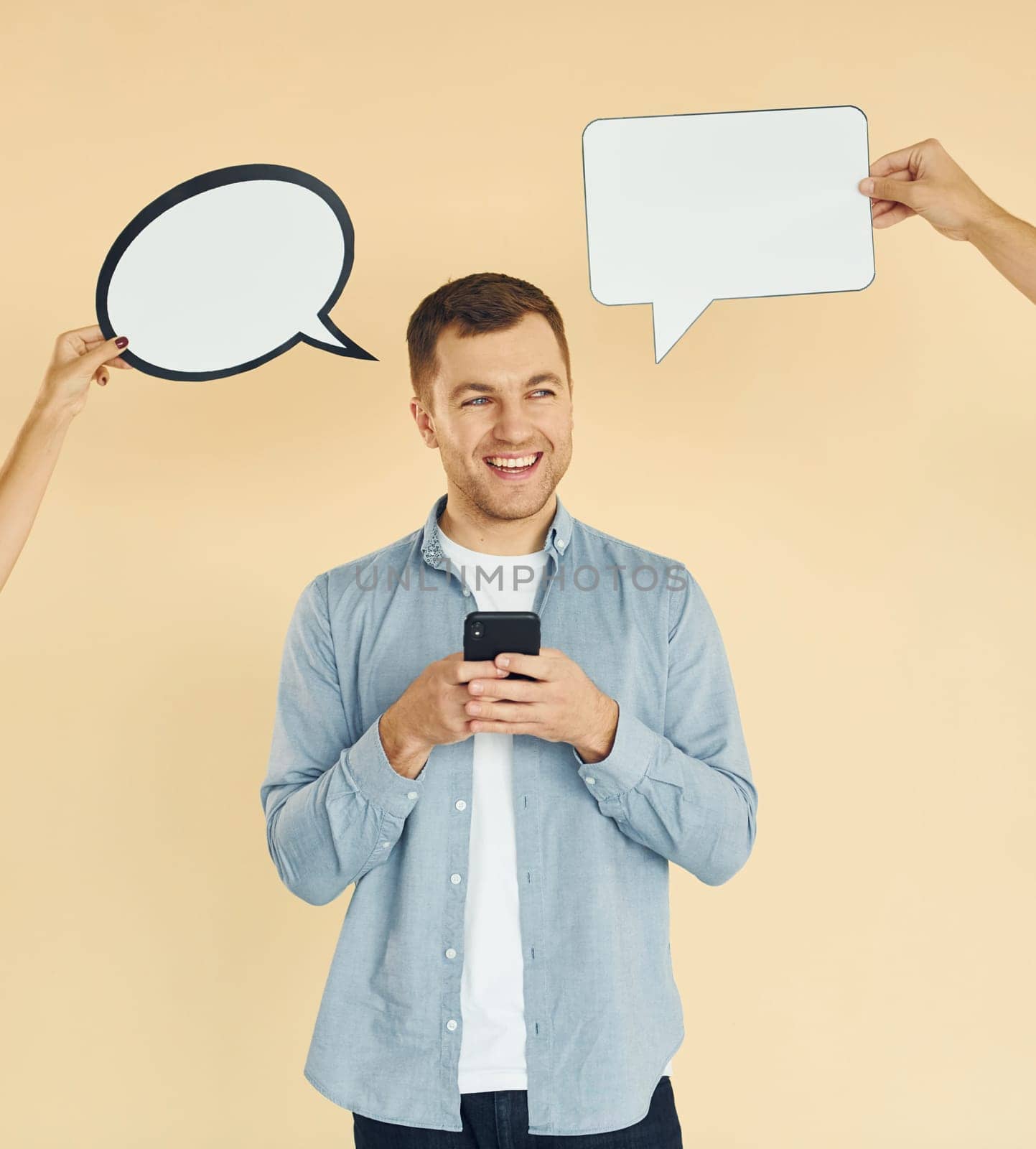 Holding smartphone. Many ideas. Man standing in the studio with empty signs for the text.