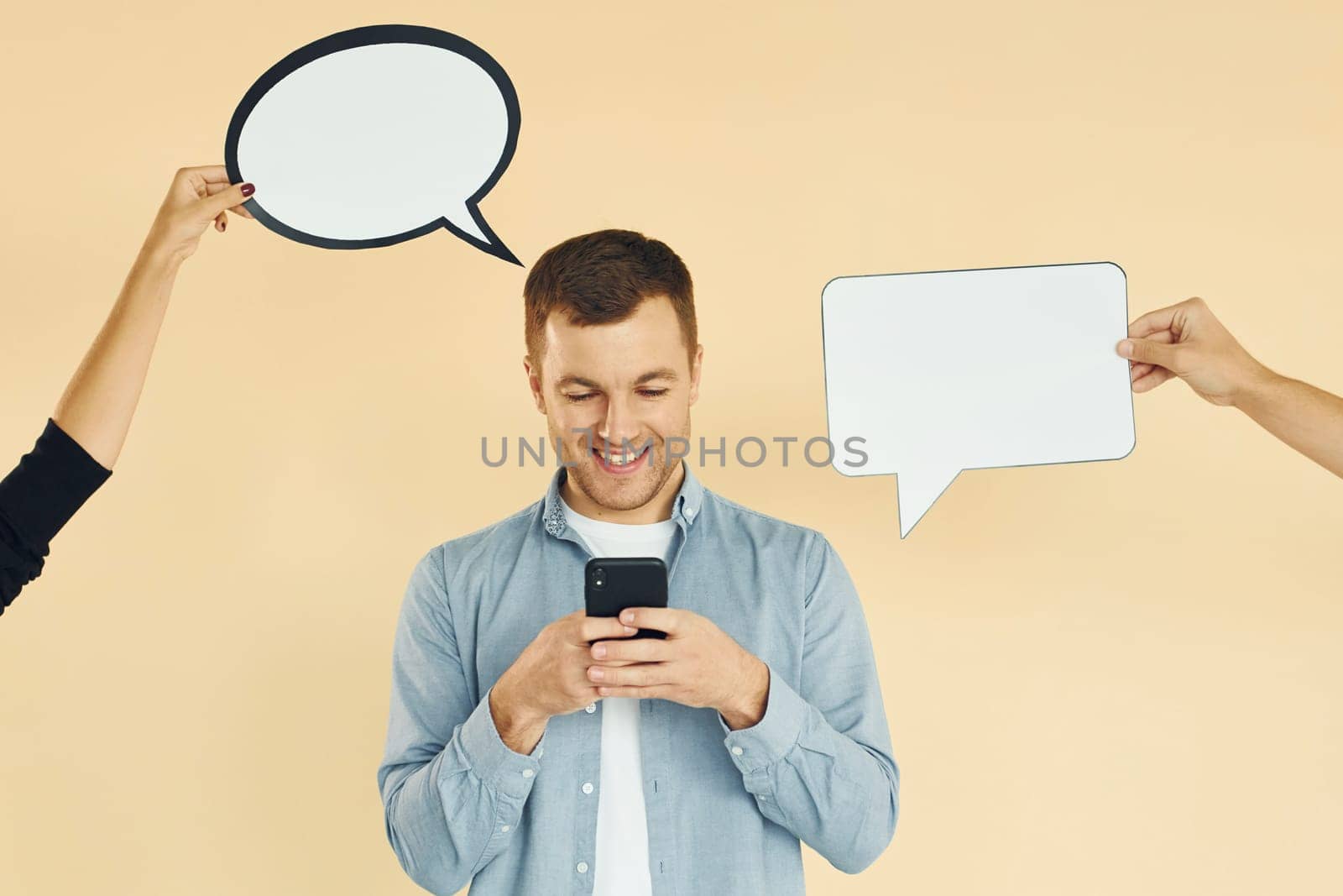 Holding smartphone. Many ideas. Man standing in the studio with empty signs for the text.