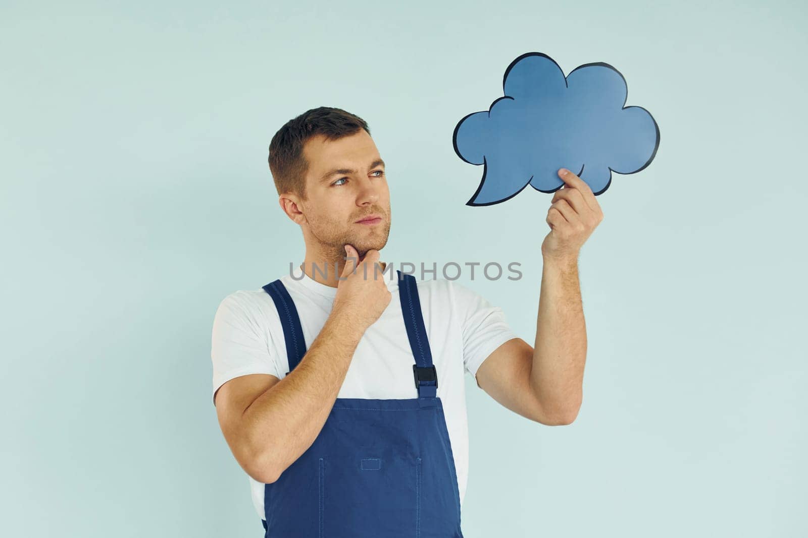 In blue uniform. Man standing in the studio with empty signs for the text.