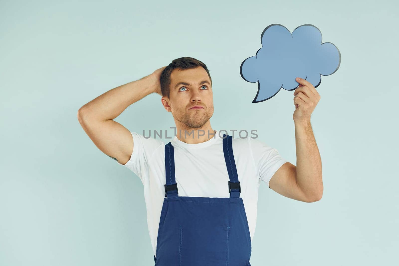 In blue uniform. Man standing in the studio with empty signs for the text.
