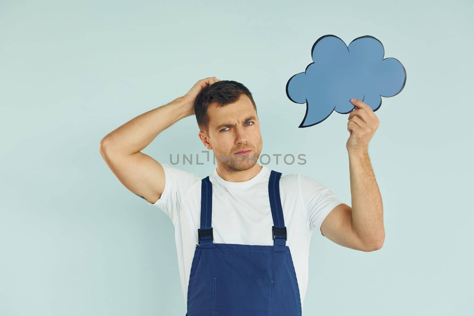 In blue uniform. Man standing in the studio with empty signs for the text.