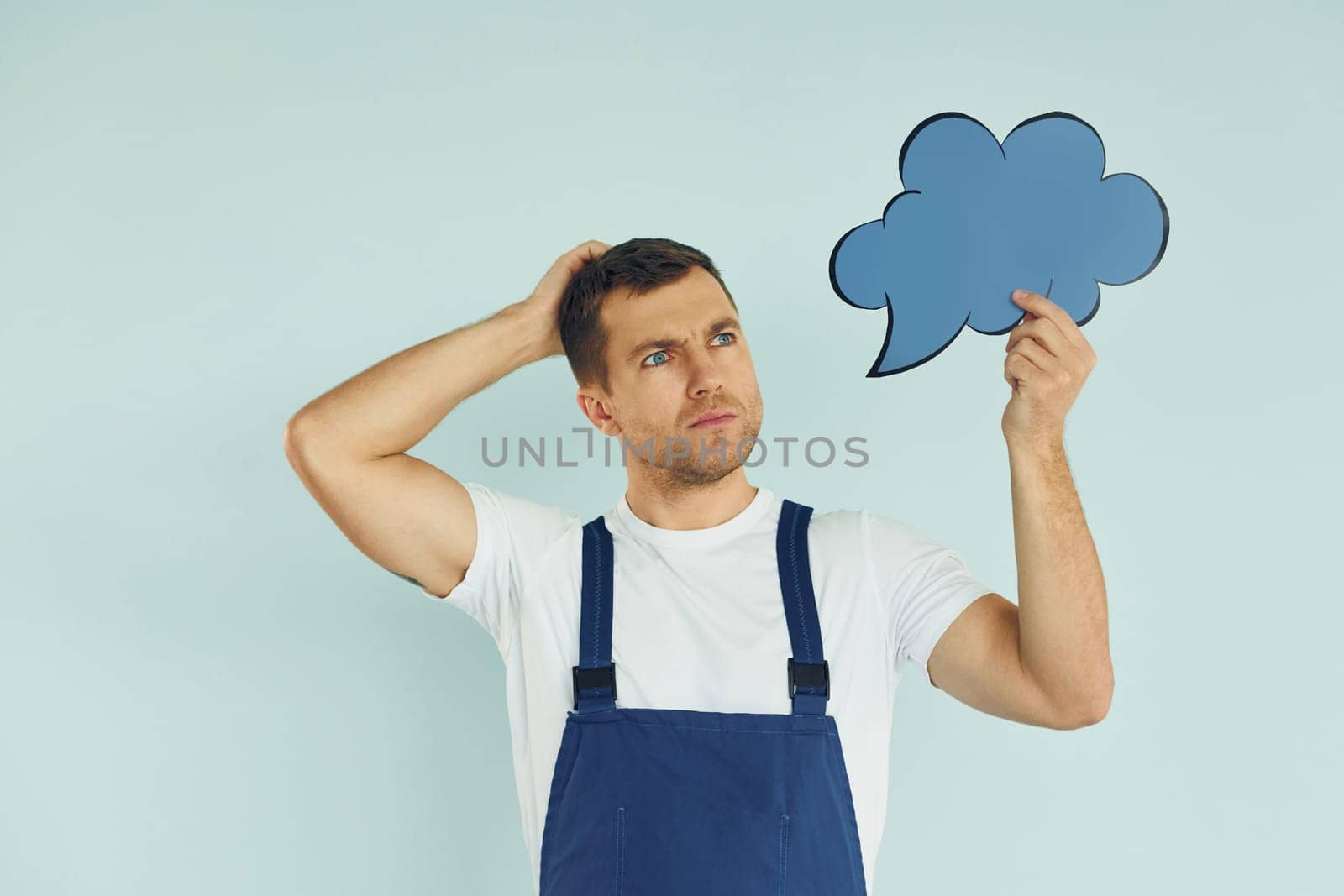 In blue uniform. Man standing in the studio with empty signs for the text.