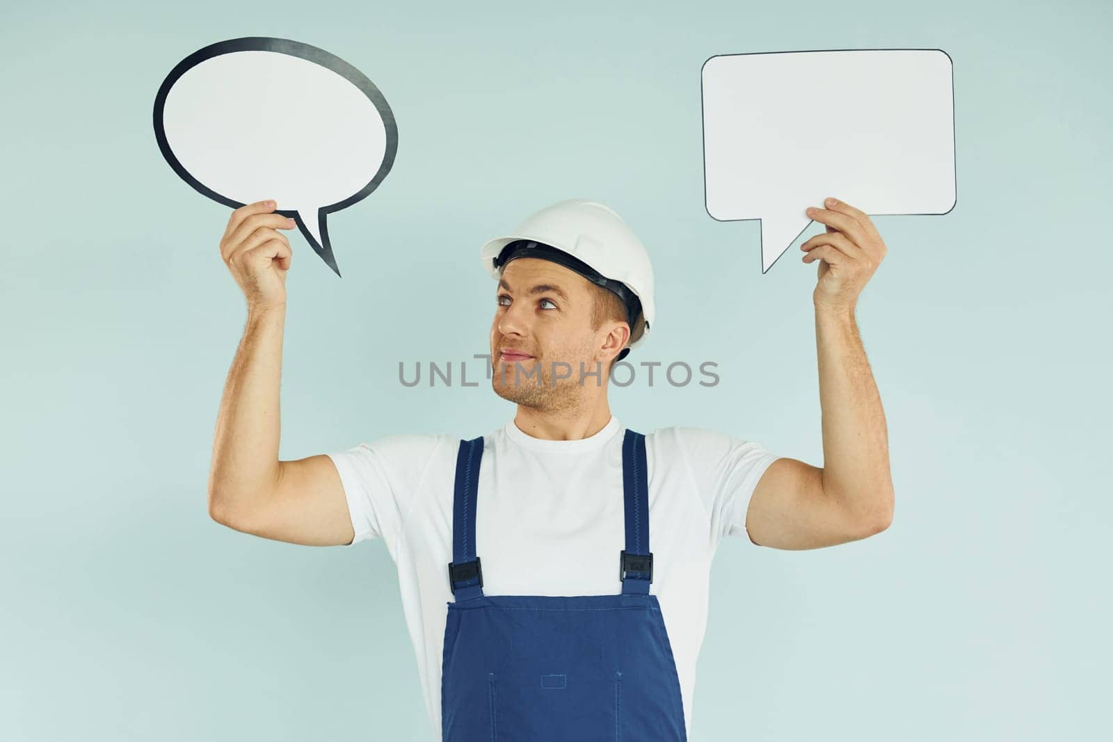 In white protective hat. Man standing in the studio with empty signs for the text.