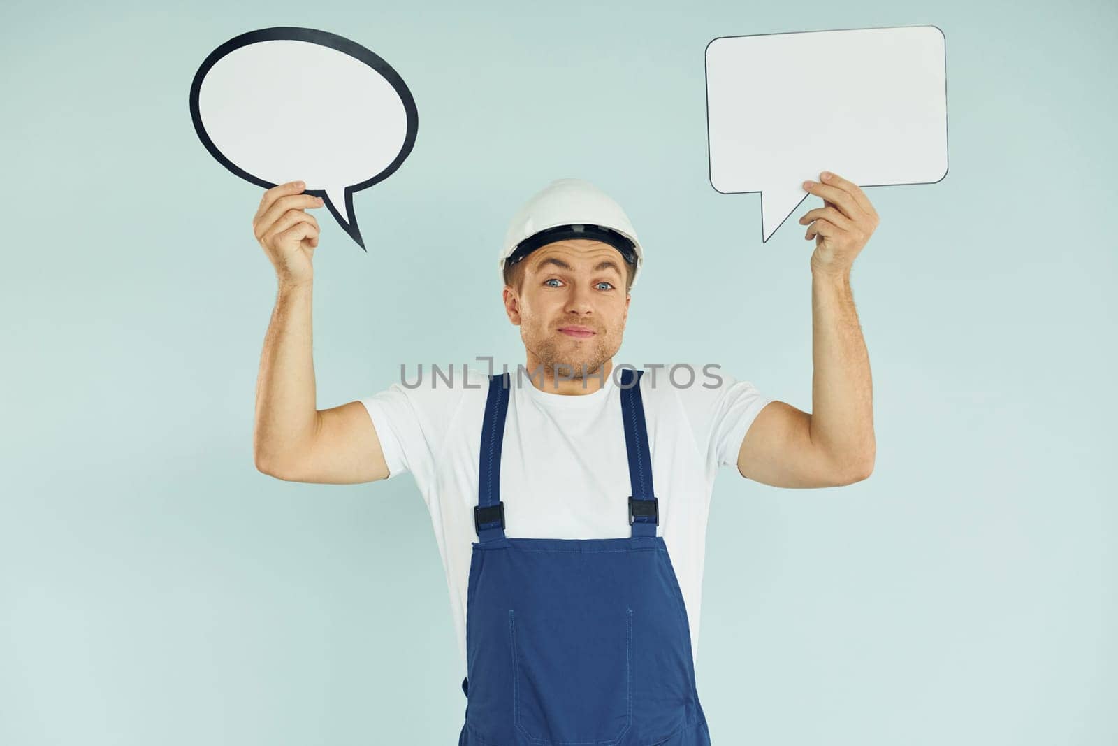 In white protective hat. Man standing in the studio with empty signs for the text.