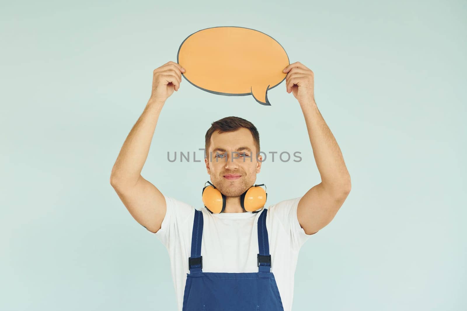 With big headphones on neck. Man standing in the studio with empty signs for the text.