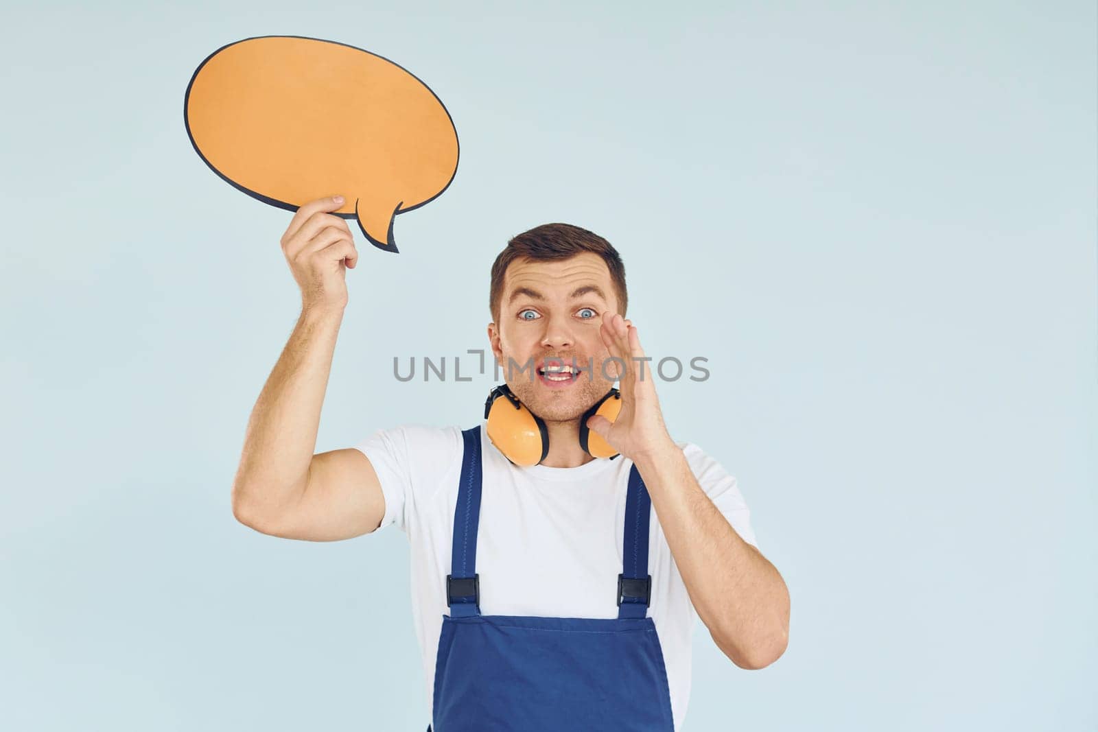 With big headphones on neck. Man standing in the studio with empty signs for the text.