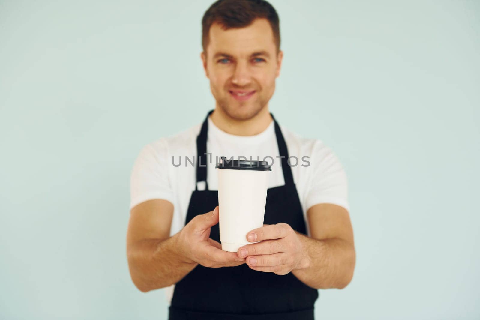 Man in uniform standing in the studio with drink in hands.