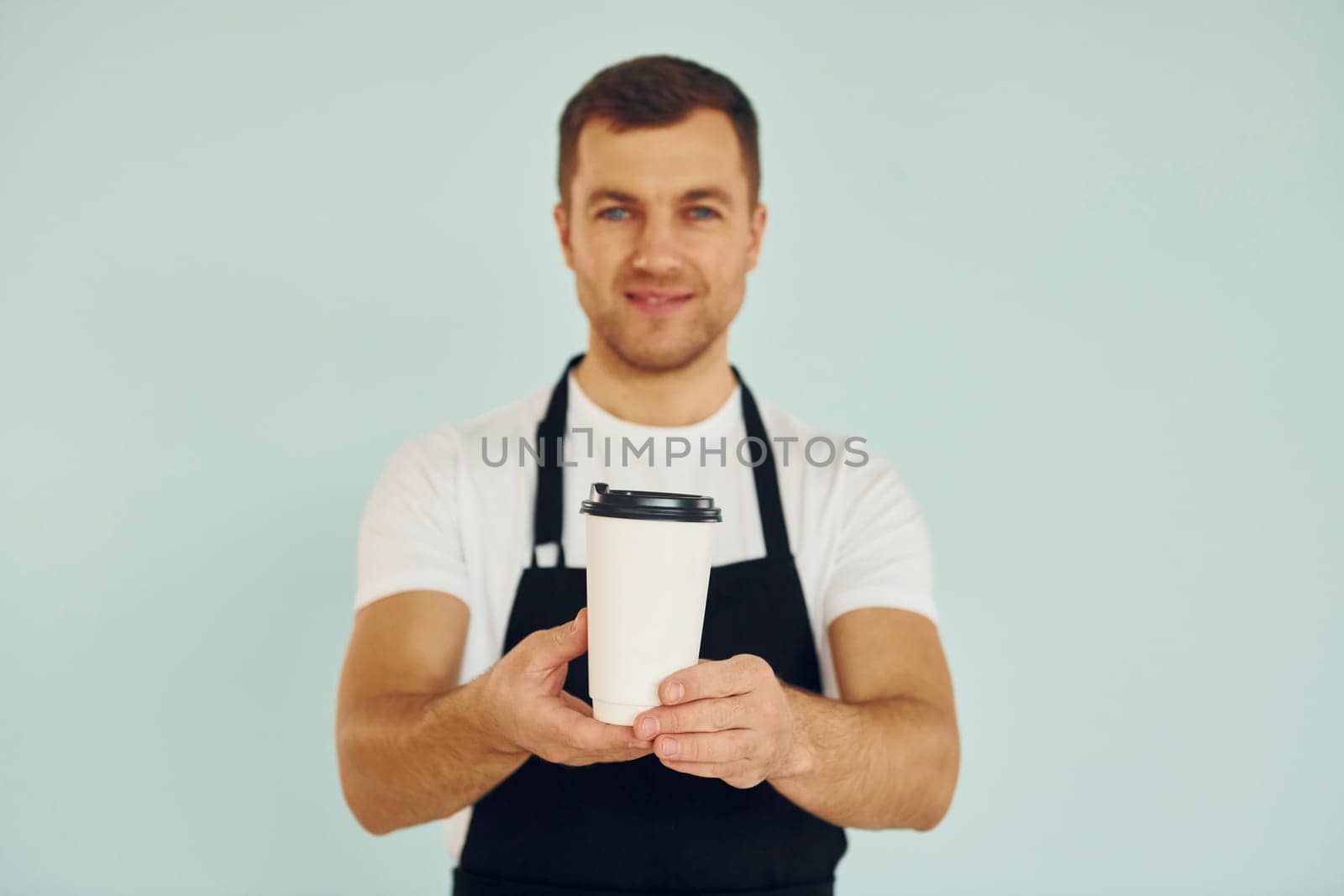 Man in uniform standing in the studio with drink in hands.