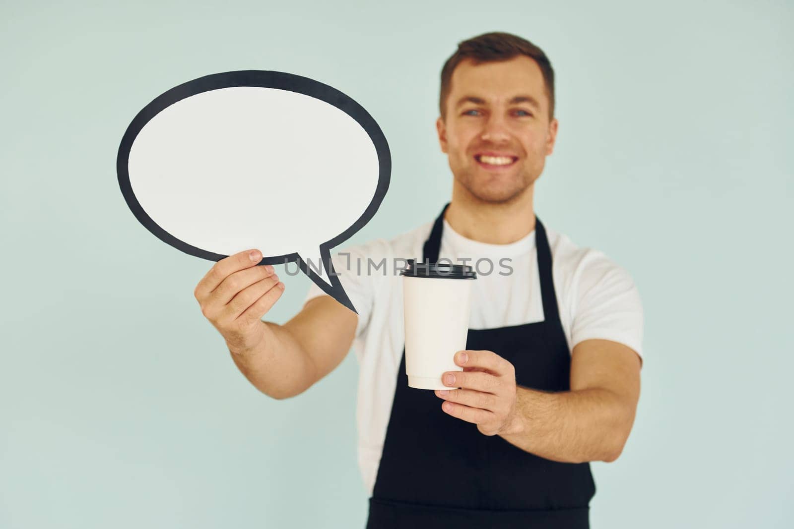 Holding drink in hand. Man standing in the studio with empty signs for the text.