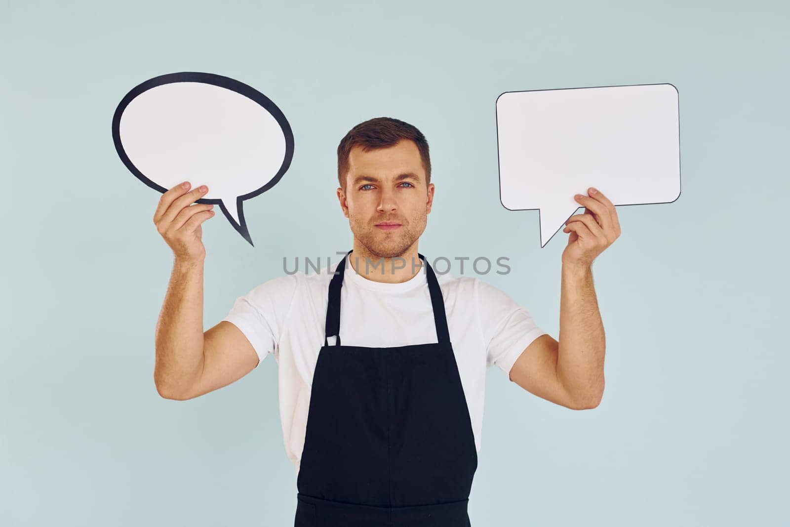 Hard choice between two ideas. Man standing in the studio with empty signs for the text.