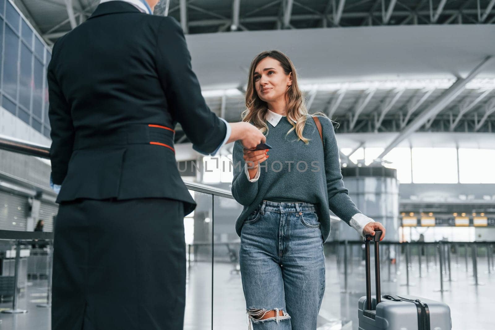 With documents. Young female tourist is in the airport at daytime.