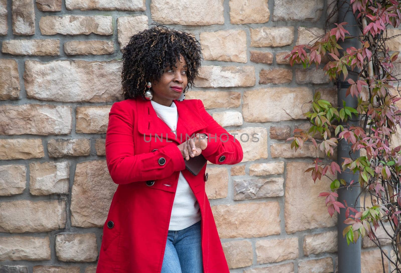 serious african american woman looks impatiently at her wrist watch near house while waiting for her husband, High quality photo