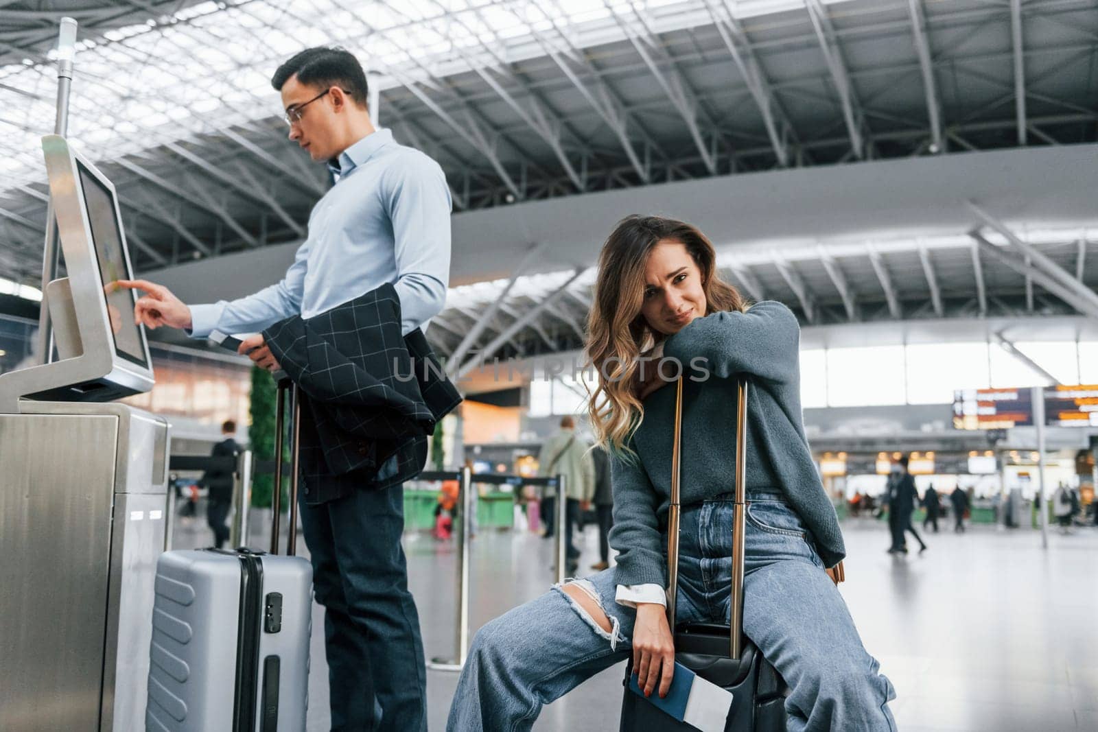 Woman is tired. Young couple is in the airport together by Standret
