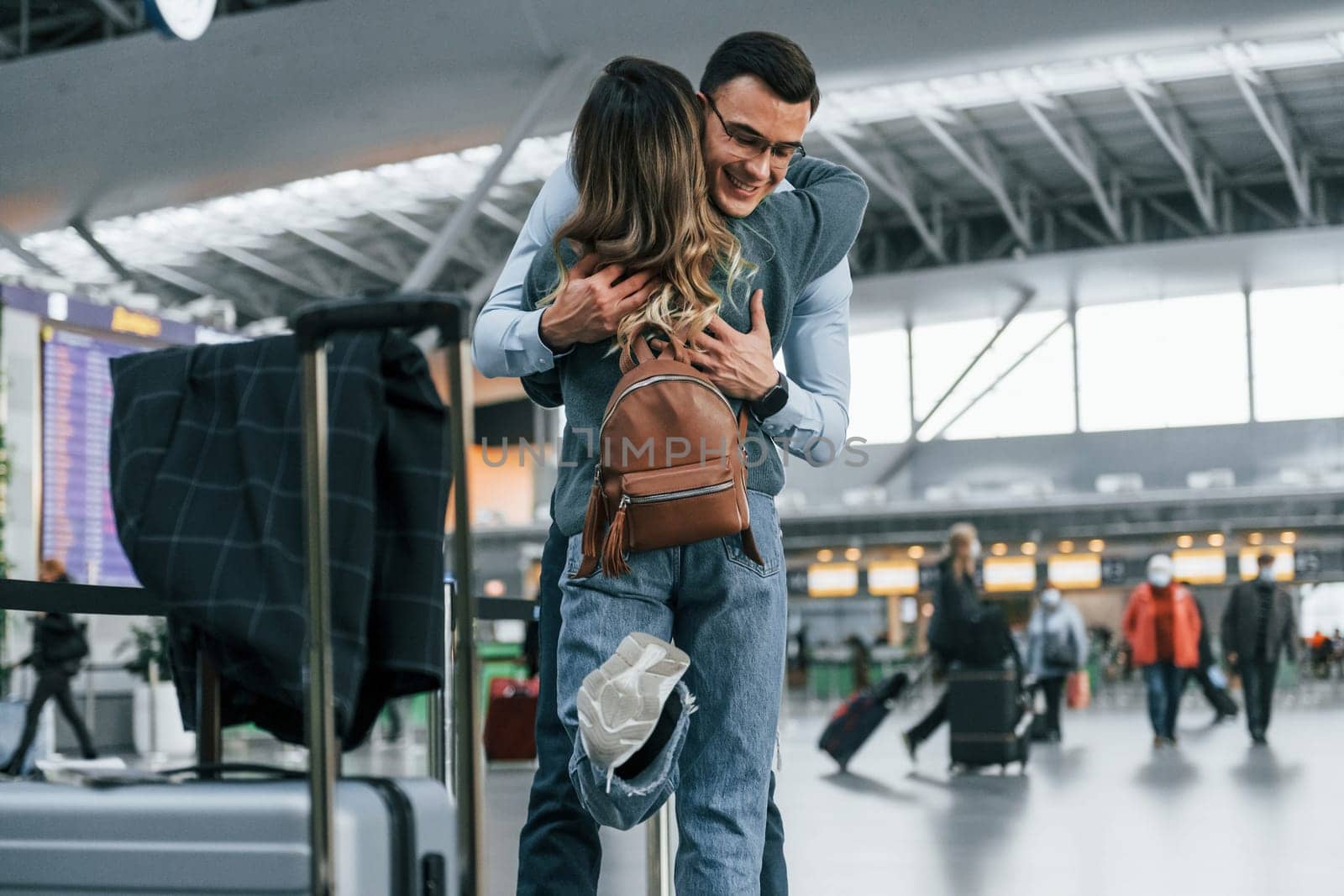 Embracing each other. Young couple is in the airport together by Standret