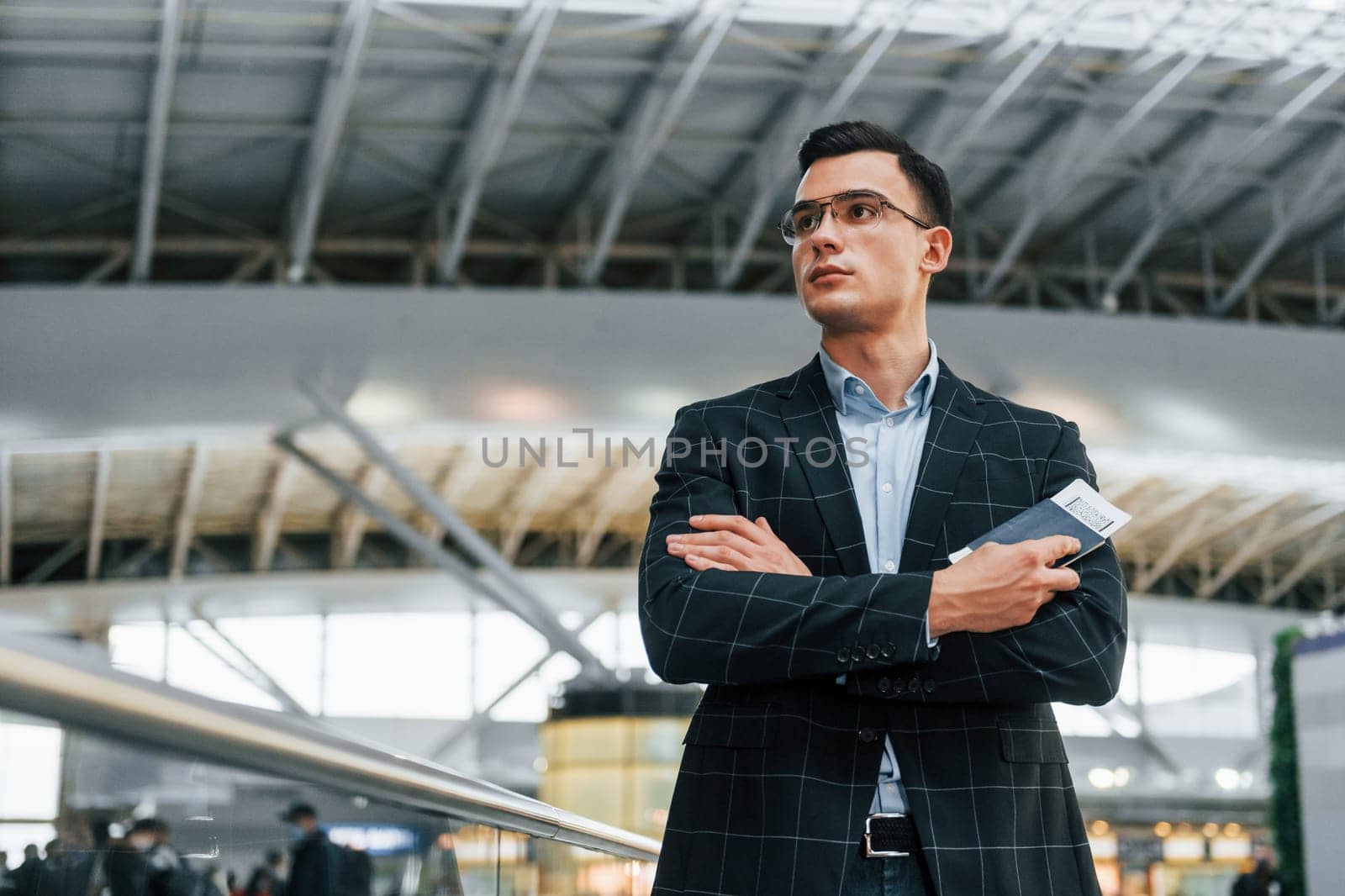 Serious look. Young businessman in formal clothes is in the airport at daytime.