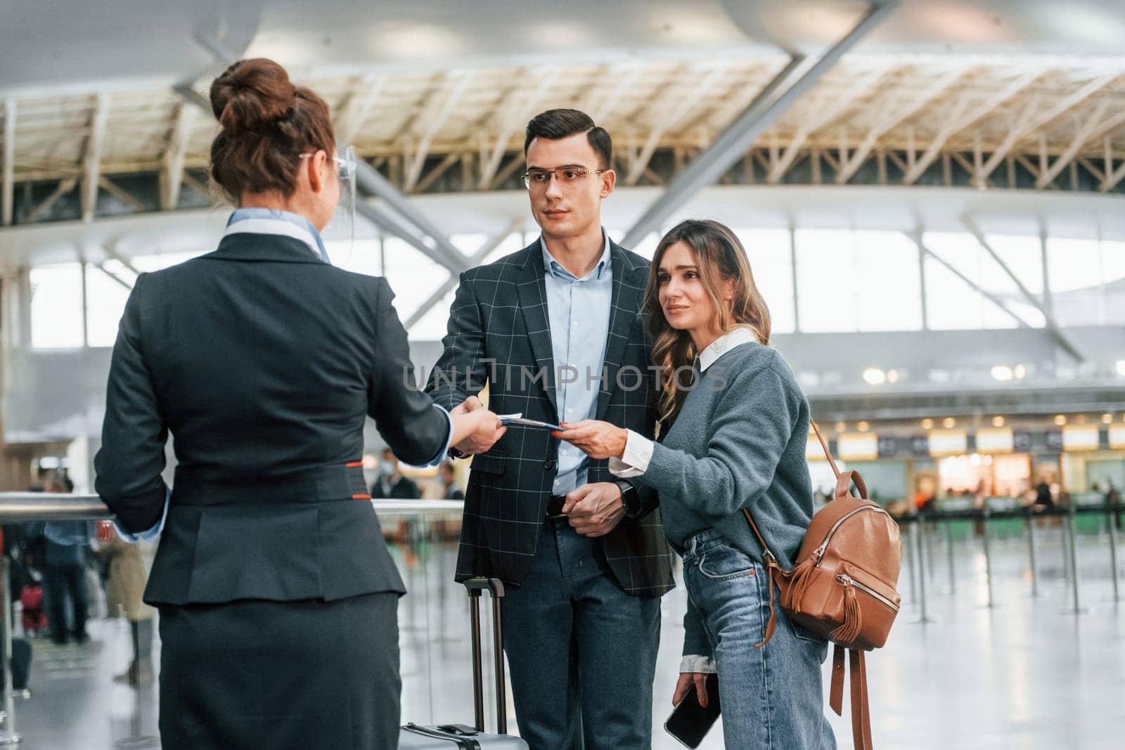 Giving the documents. Young couple is in the airport together.
