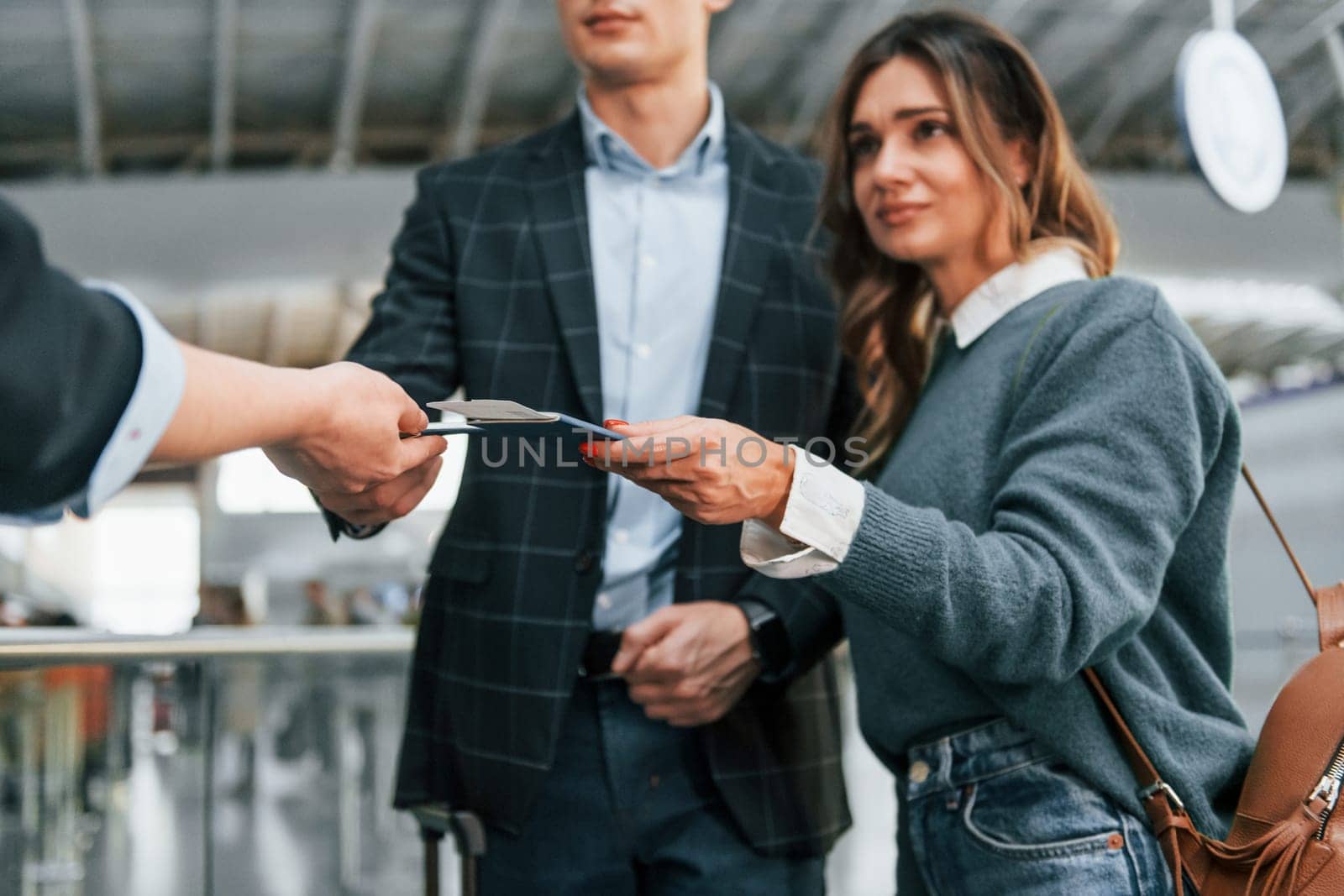 Giving the documents. Young couple is in the airport together.