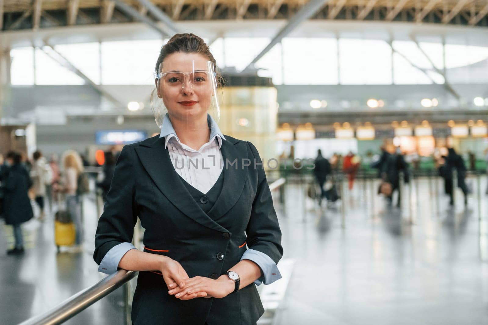 Female aurport worker in formal clothes is standing indoors.
