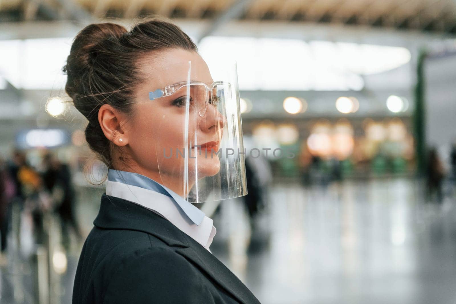 Side view. Female aurport worker in formal clothes is standing indoors.
