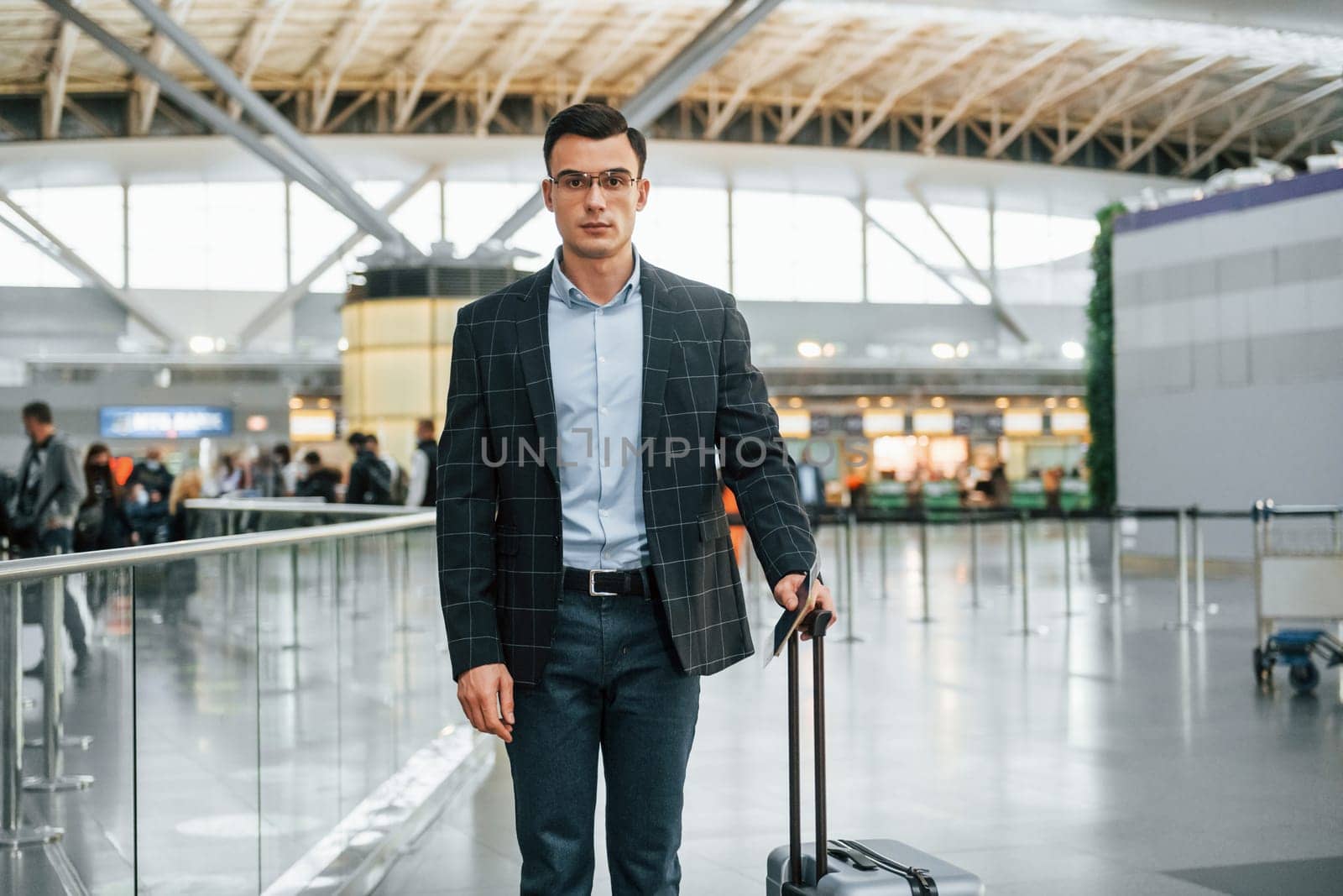Young businessman in formal clothes is in the airport at daytime.