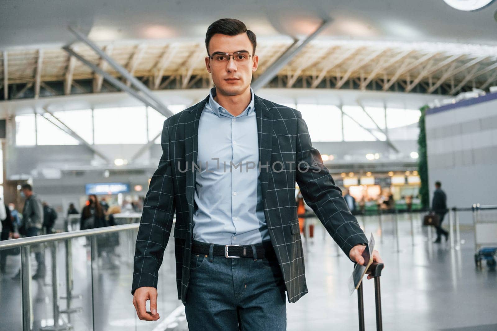 With lugagge. Young businessman in formal clothes is in the airport at daytime.