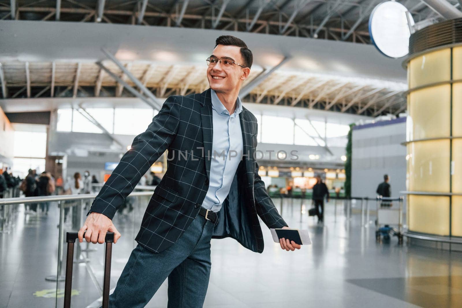 With lugagge. Young businessman in formal clothes is in the airport at daytime.