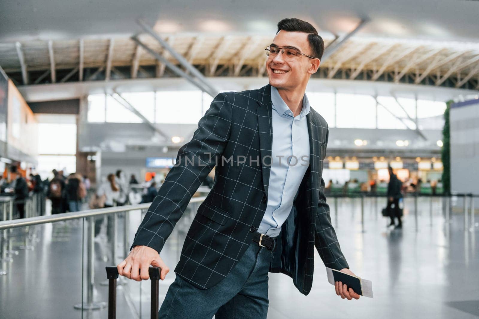 With lugagge. Young businessman in formal clothes is in the airport at daytime.