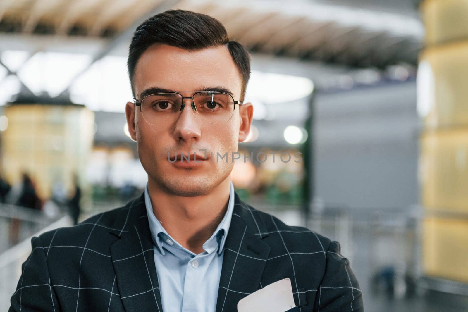 Young businessman in formal clothes is in the airport at daytime.
