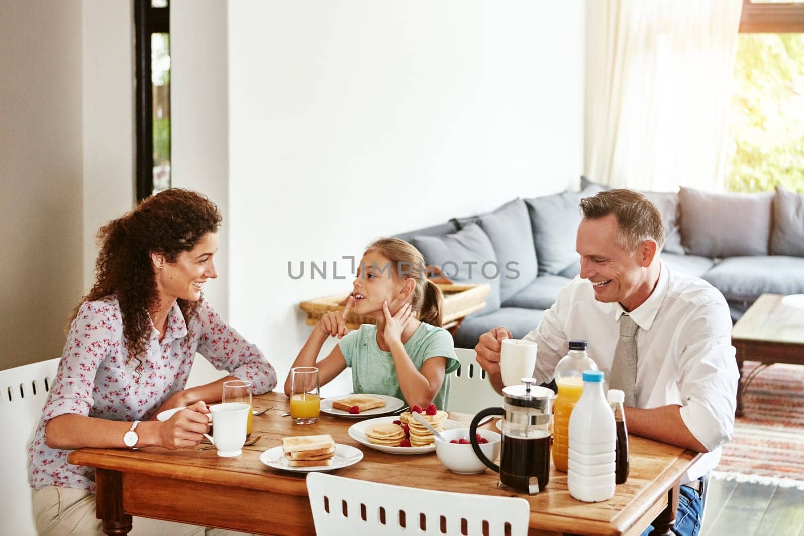 Family time is all about sharing stories. a family having breakfast together at home. by YuriArcurs