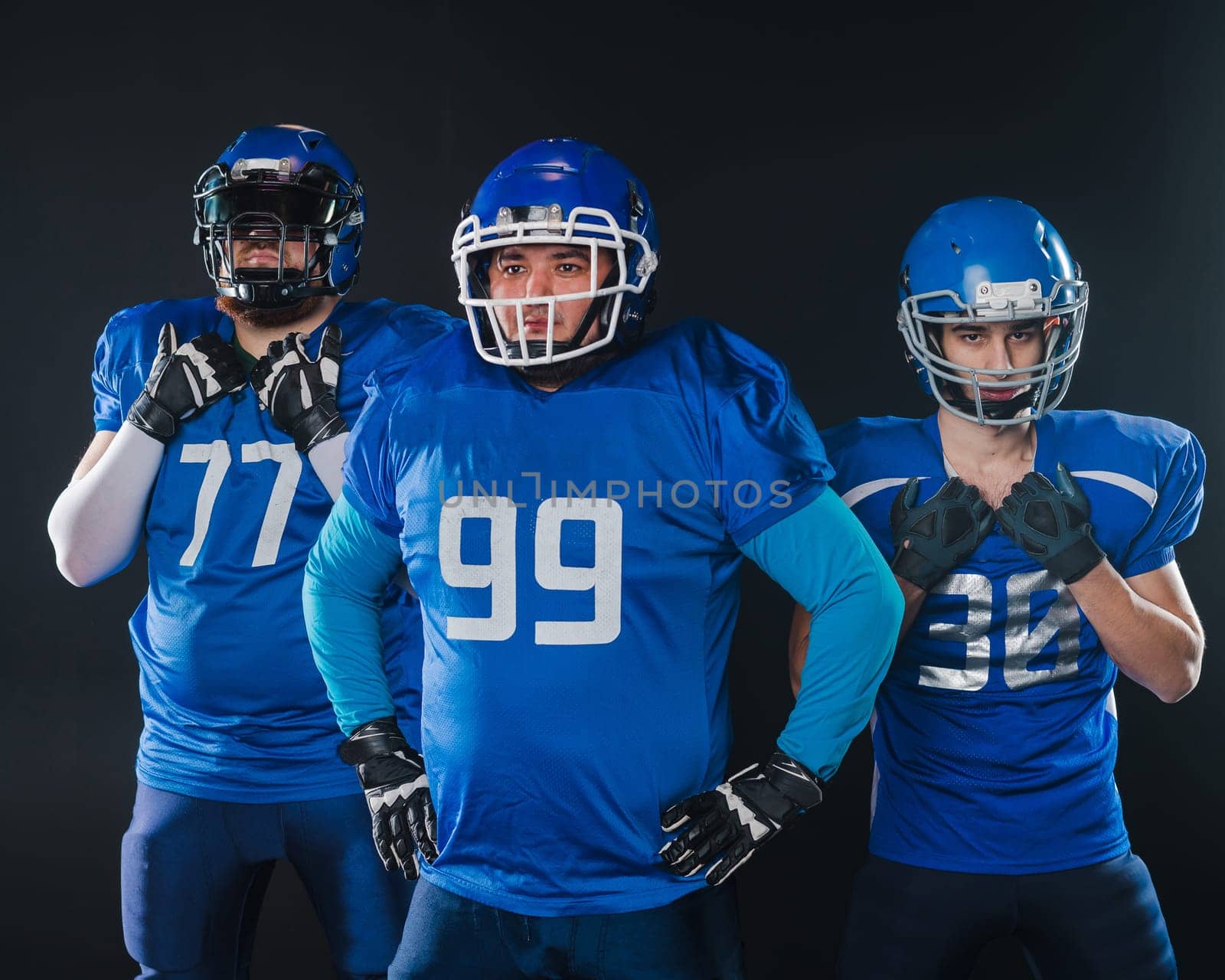Portrait of three men in blue uniforms for American football on a black background. by mrwed54