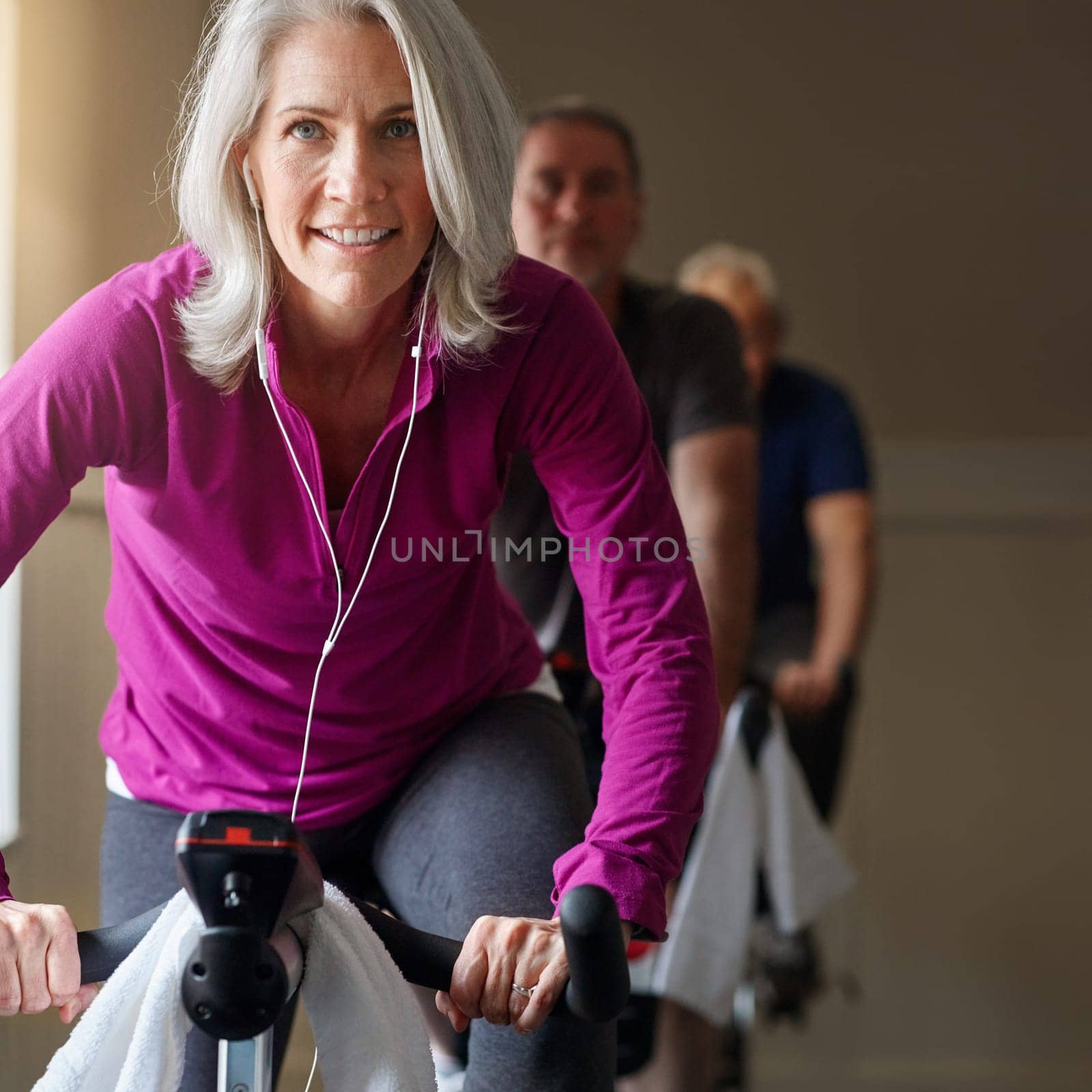 Our determination defines us not our age. a group of seniors having a spinning class at the gym. by YuriArcurs