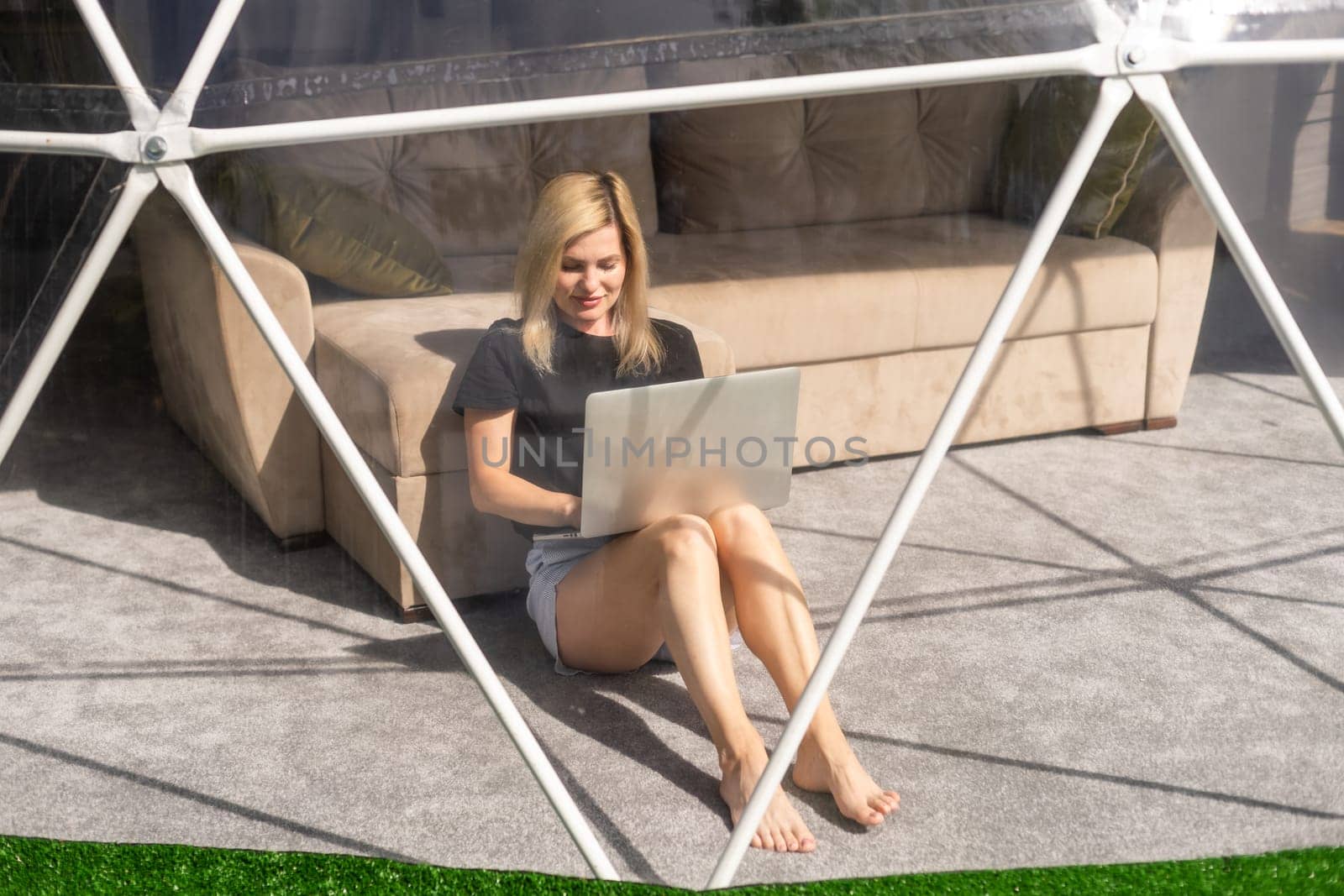 Transparent bubble tent at glamping, Lush forest around and interior. Woman with laptop.