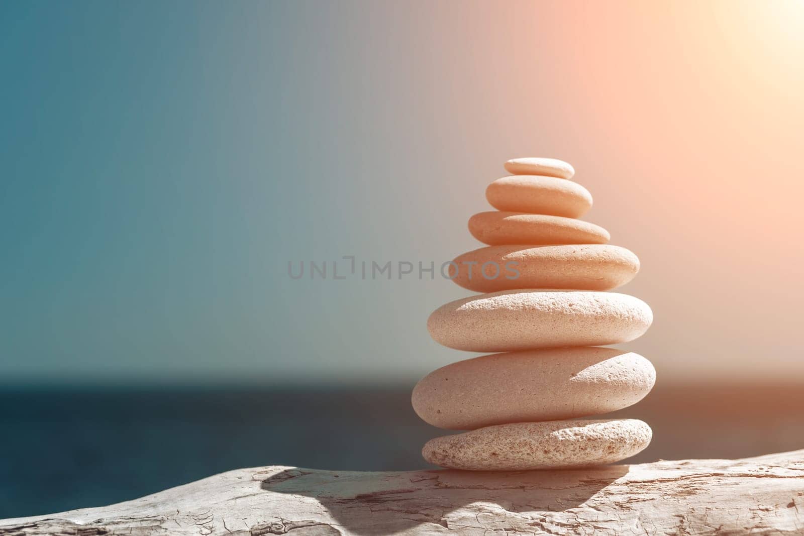 Pyramid stones on the seashore with warm sunset on the sea background. Happy holidays. Pebble beach, calm sea, travel destination. Concept of happy vacation on the sea, meditation, spa, calmness.