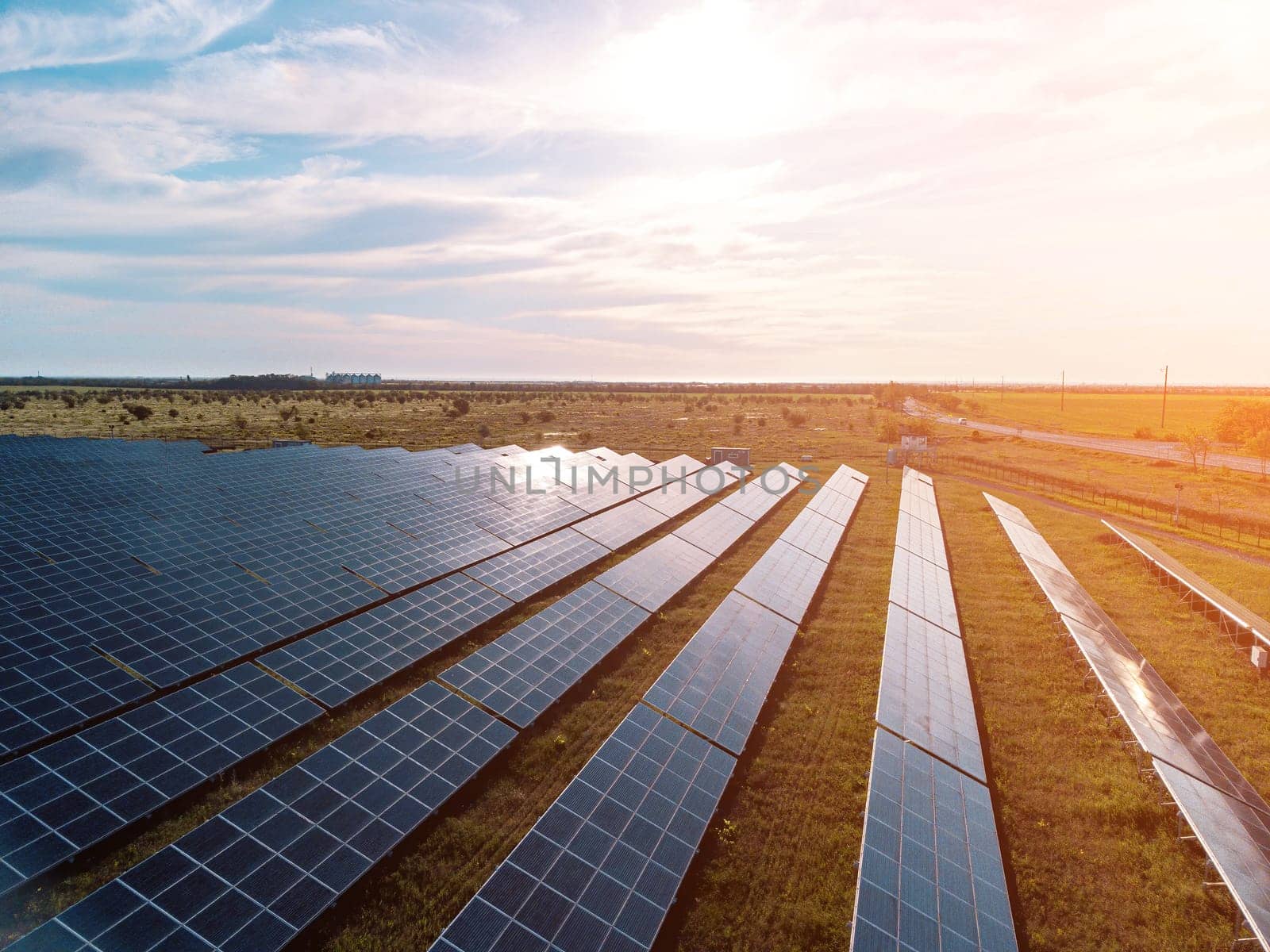 Aerial top view of a solar panels power plant. Photovoltaic solar panels at sunrise and sunset in countryside from above. Modern technology, climate care, earth saving, renewable energy concept