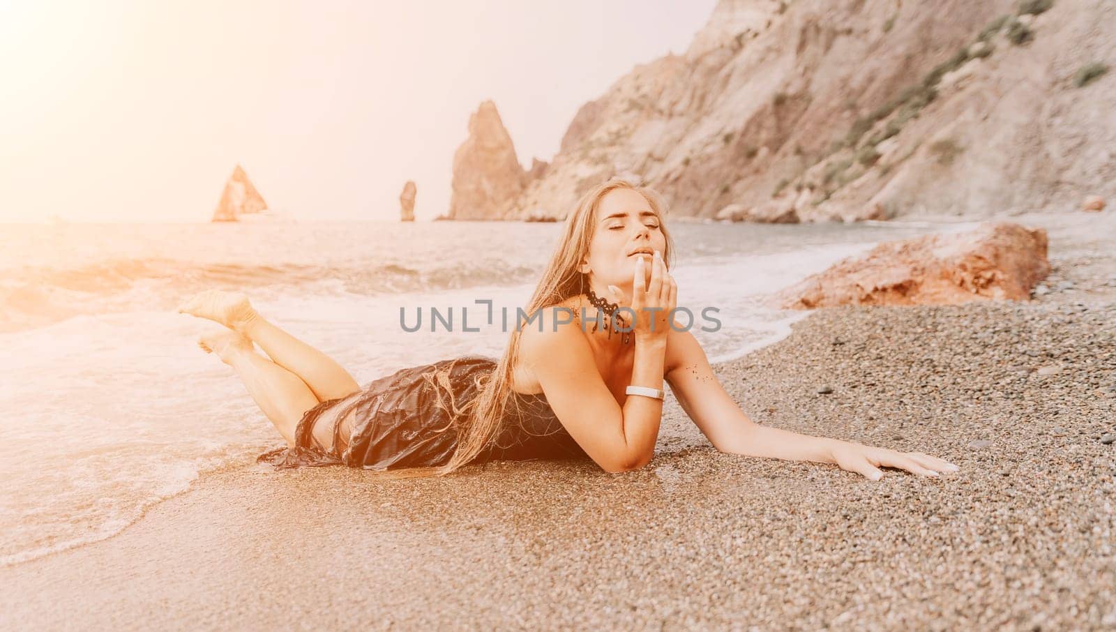 Woman travel sea. Young Happy woman in a long red dress posing on a beach near the sea on background of volcanic rocks, like in Iceland, sharing travel adventure journey