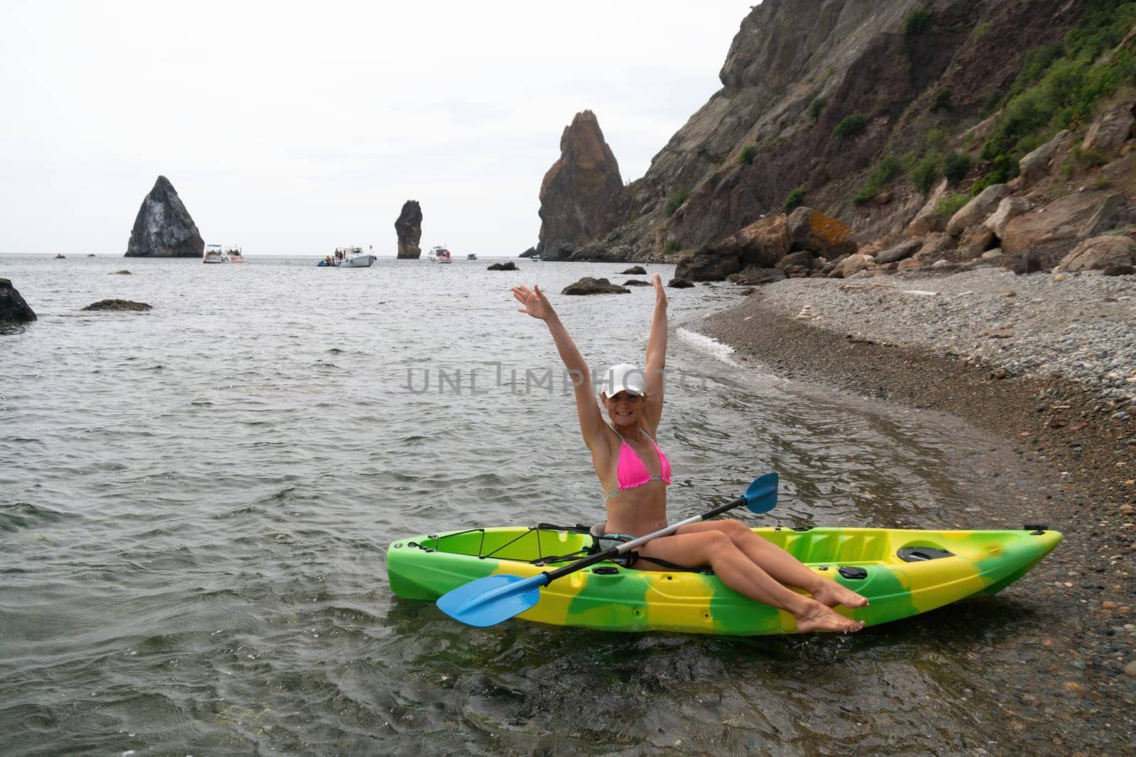 Woman kayak sea. Happy tourist enjoy taking picture outdoors for memories. Woman traveler posing in kayak canoe at sea surrounded by volcanic mountains, sharing travel adventure in kayak by panophotograph